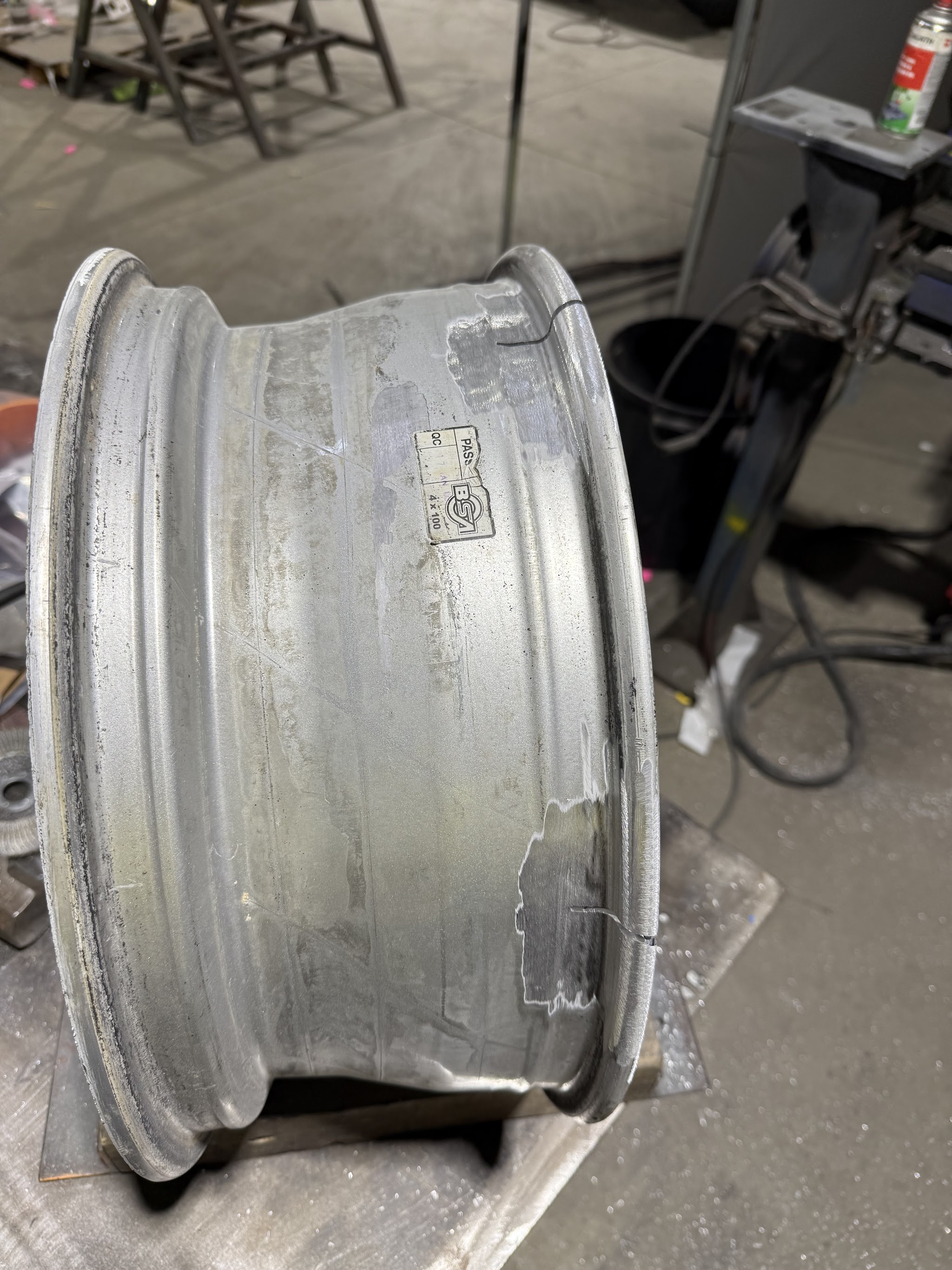 A bare alloy rim on a repair stand, welded and machined along the barrel, part way through the job