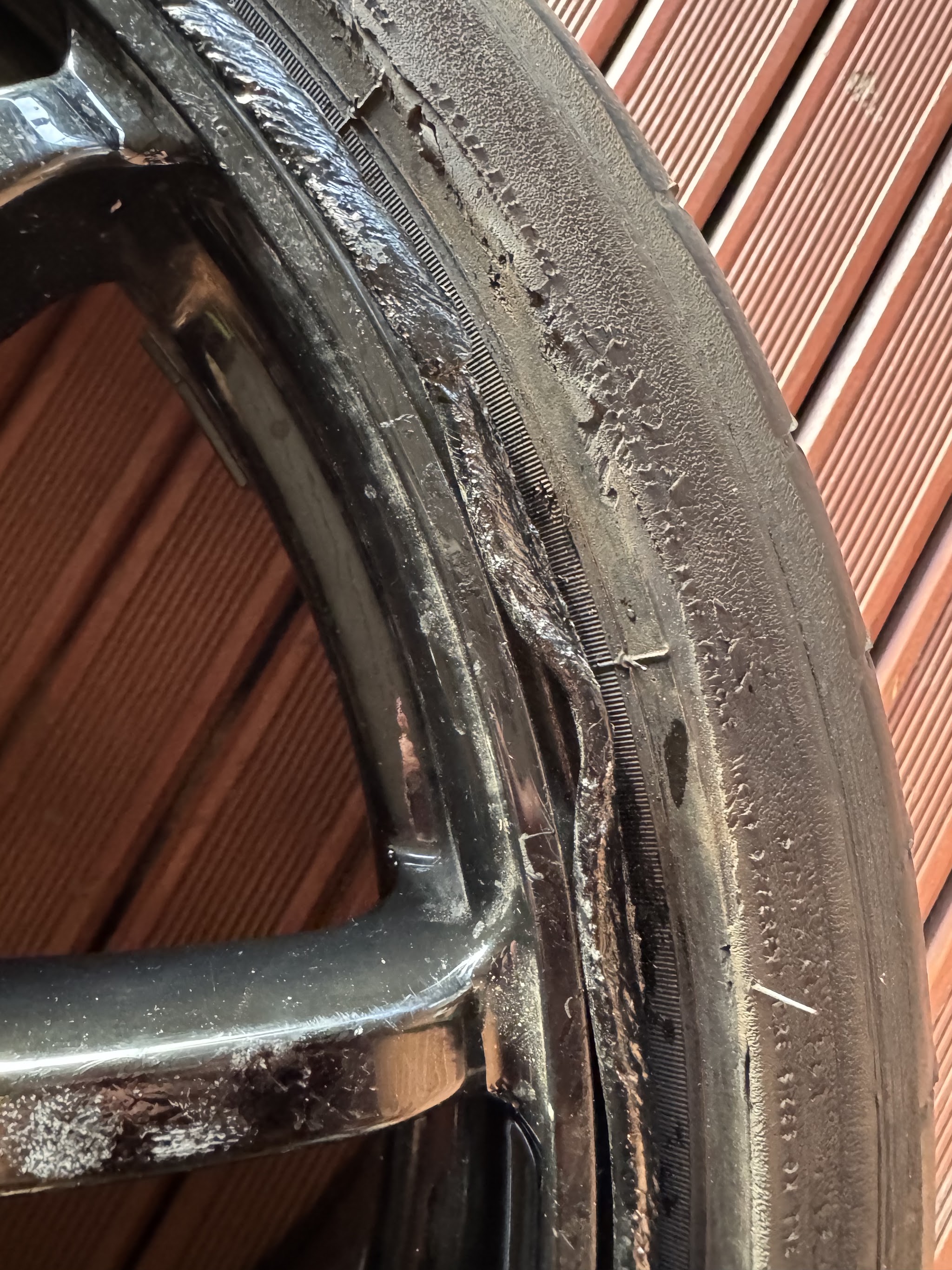 A badly damaged alloy wheel lip, torn and peeled away from the rim, before repair