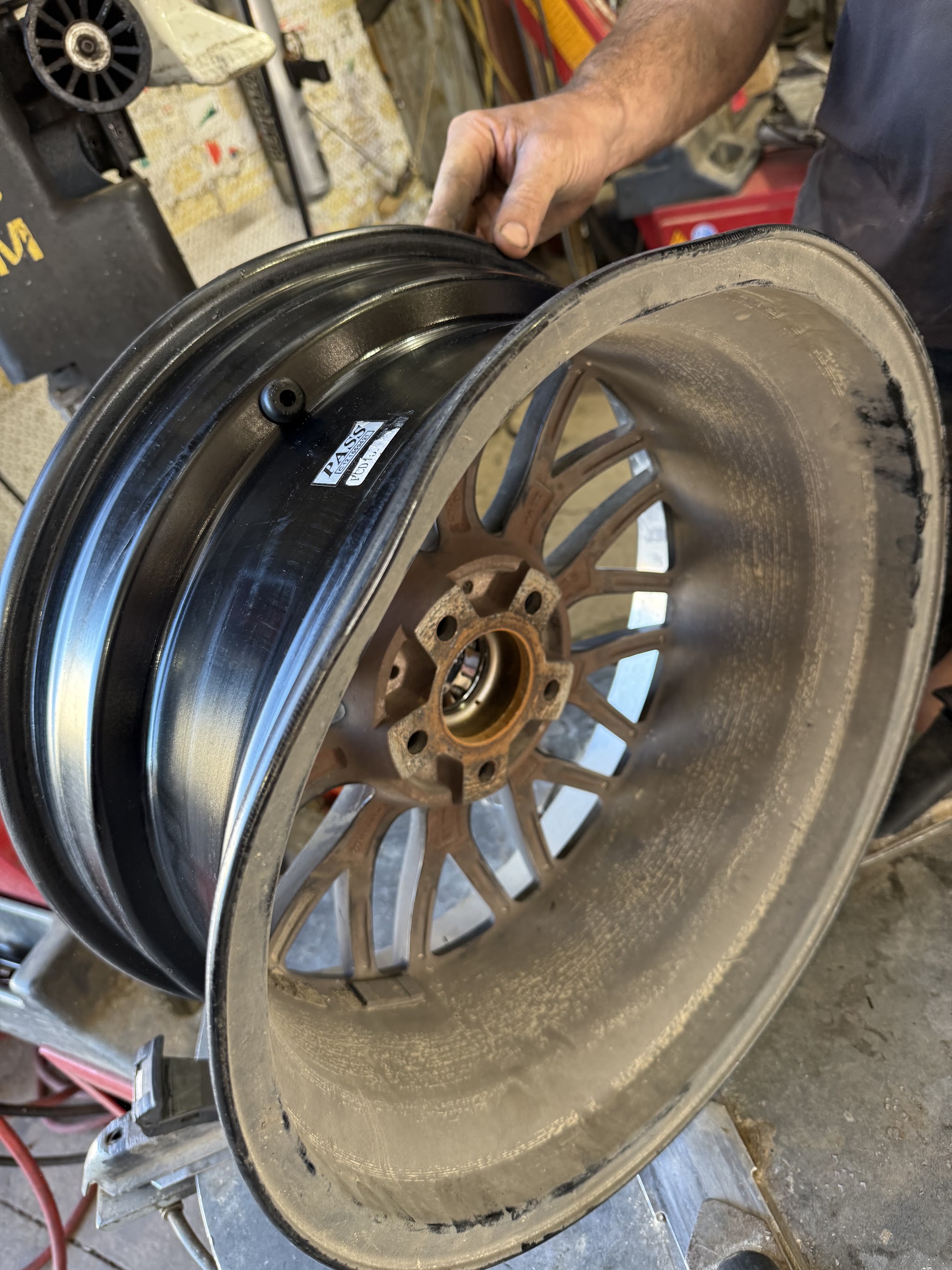 Cameron holding a finished two tone polished and black alloy wheel in the workshop